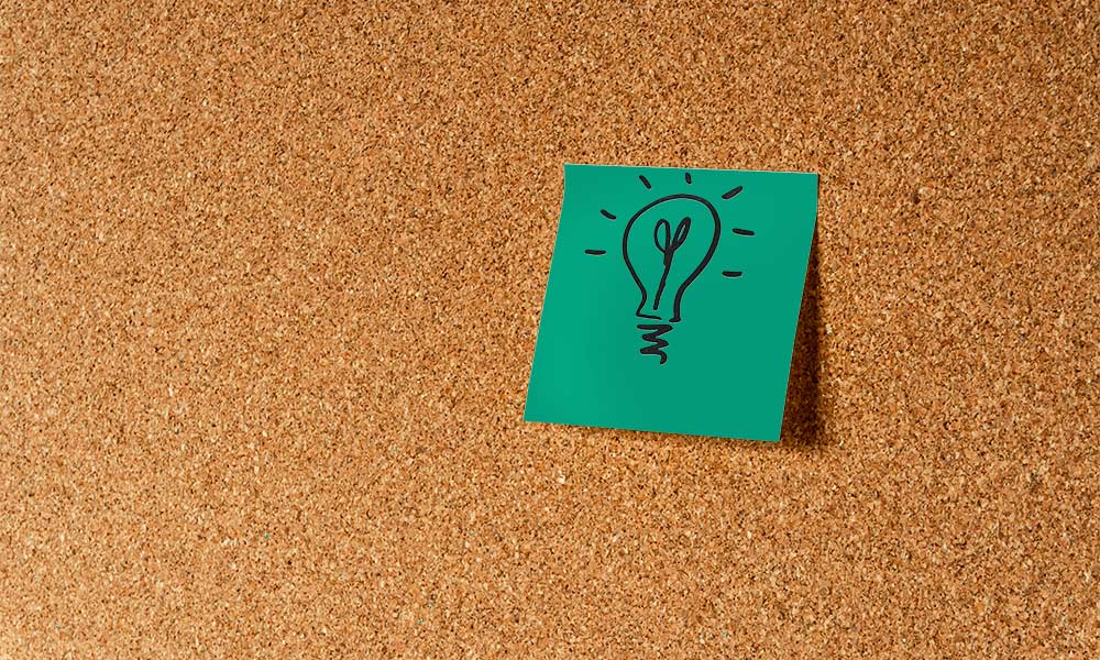 Post-it mit einer gezeichneten Glühbirne an einer Korkpinnwand